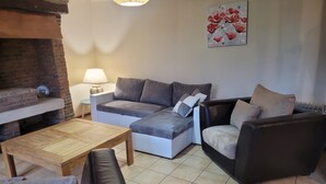 A cozy living room with a sectional sofa, a small table, and a fireplace. - Bridge meadows (Grainville-la-Teinturière)