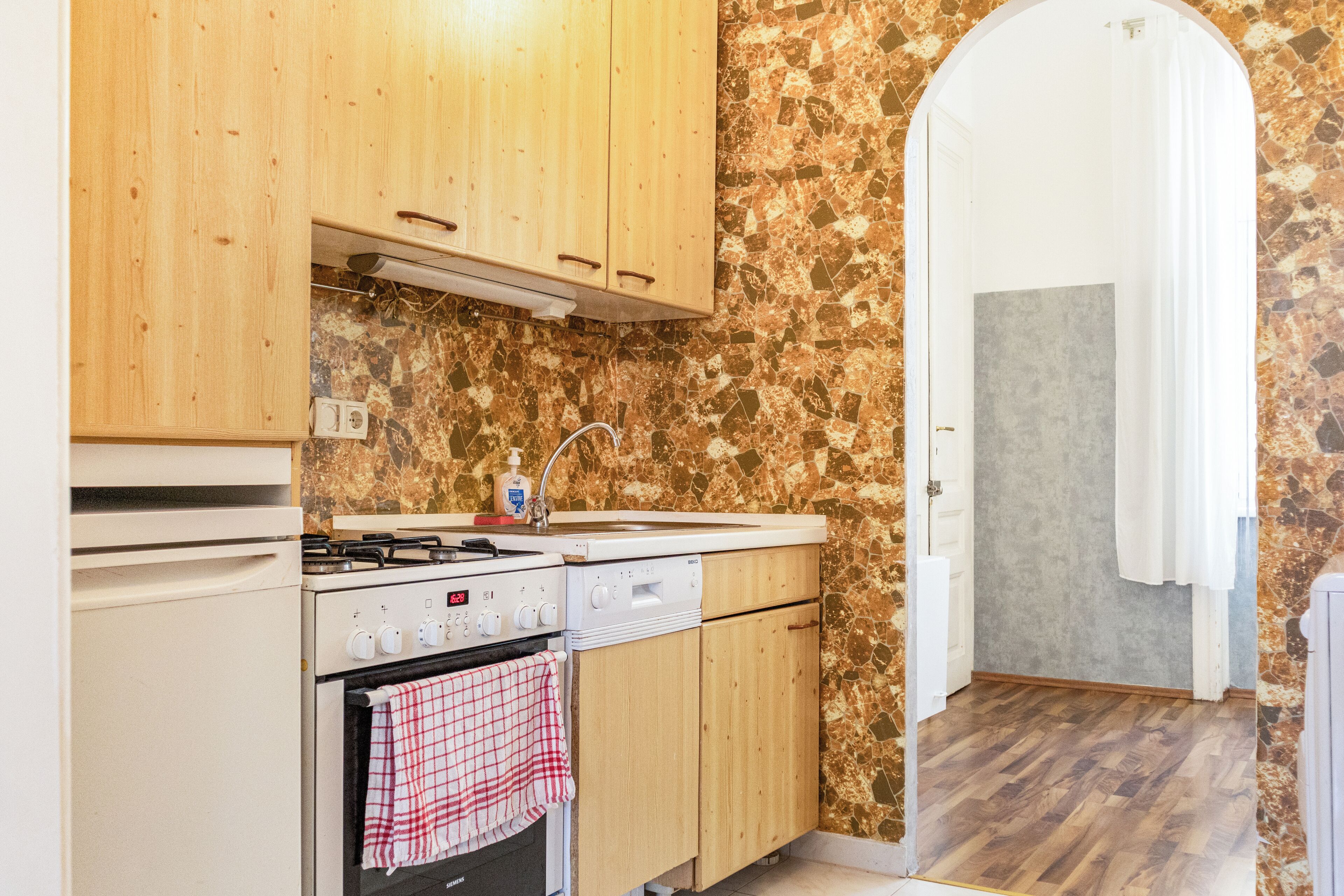 A kitchen with wooden cabinets, a stove, and a sink.