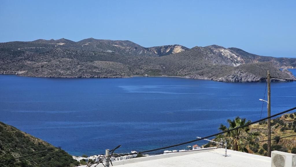 A coastal landscape with a clear view of the sea and distant mountains.