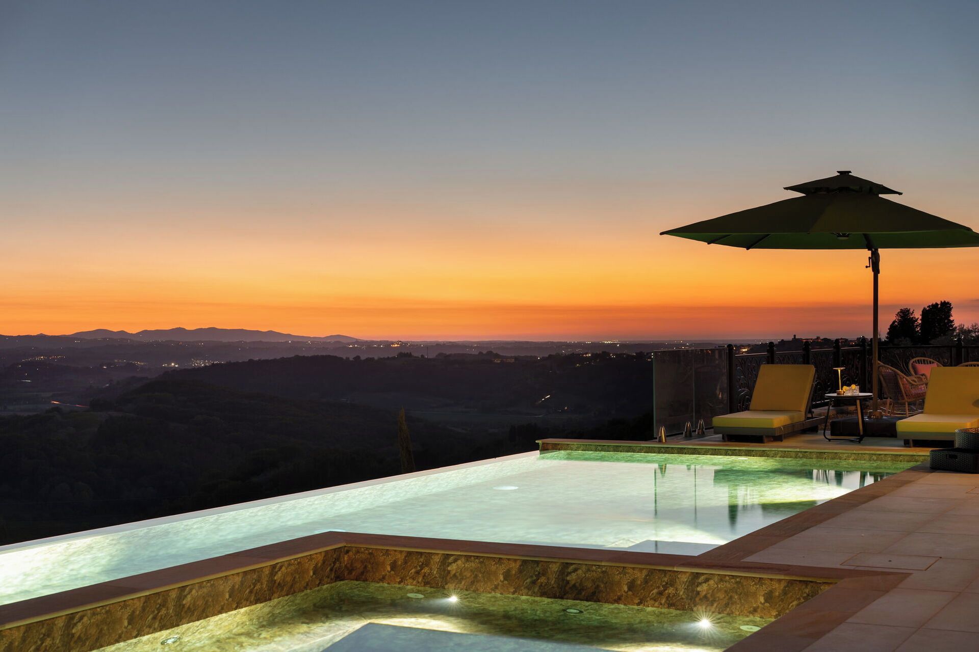 Ein Infinity-Pool mit Blick auf einen Sonnenuntergang über einem Tal.