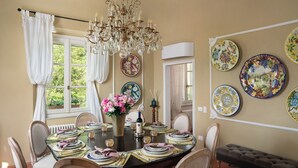 A dining room with a chandelier, floral wall plates, and a table set for four. - Stunning private villa with private pool, A/C, WIFI, hot tub, patio and panoramic view (Legoli)
