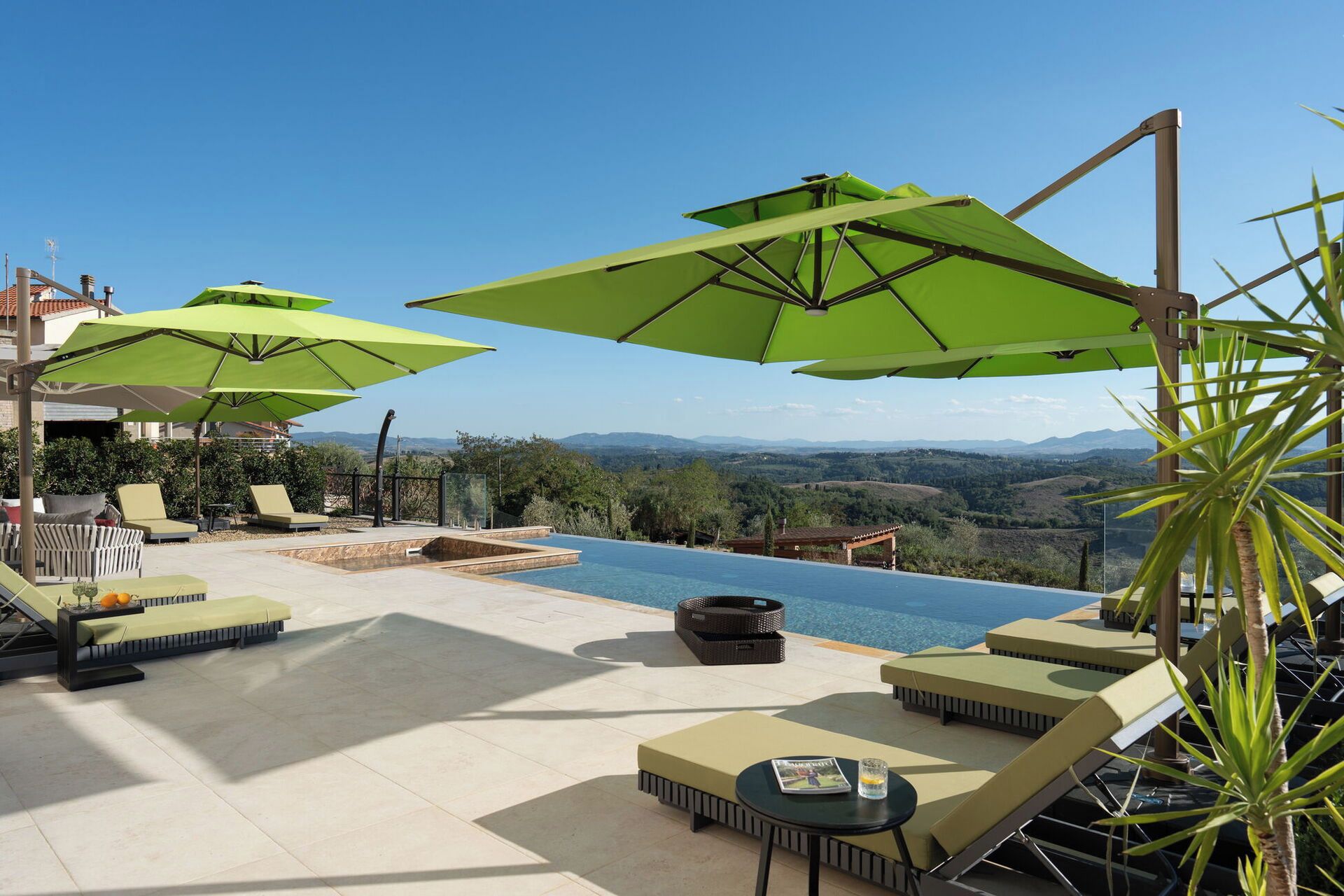 A poolside area with lounge chairs, umbrellas, and a view of the landscape.