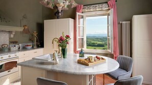 A kitchen with a large window, a chandelier, and a view of the countryside. - Stunning private villa with private pool, A/C, WIFI, hot tub, patio and panoramic view (Legoli)
