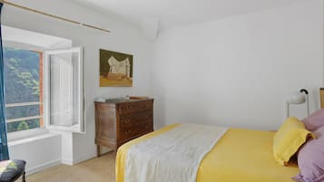Un dormitorio con cama, cómoda, un cuadro y ventana con vistas.
