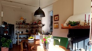 A kitchen with wooden furniture, a dining table, and a hanging light fixture.