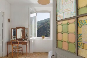 Ein Zimmer mit einem Holztisch, einem Stuhl, einem Fenster mit Bergblick und einer dekorativen Wandverkleidung.