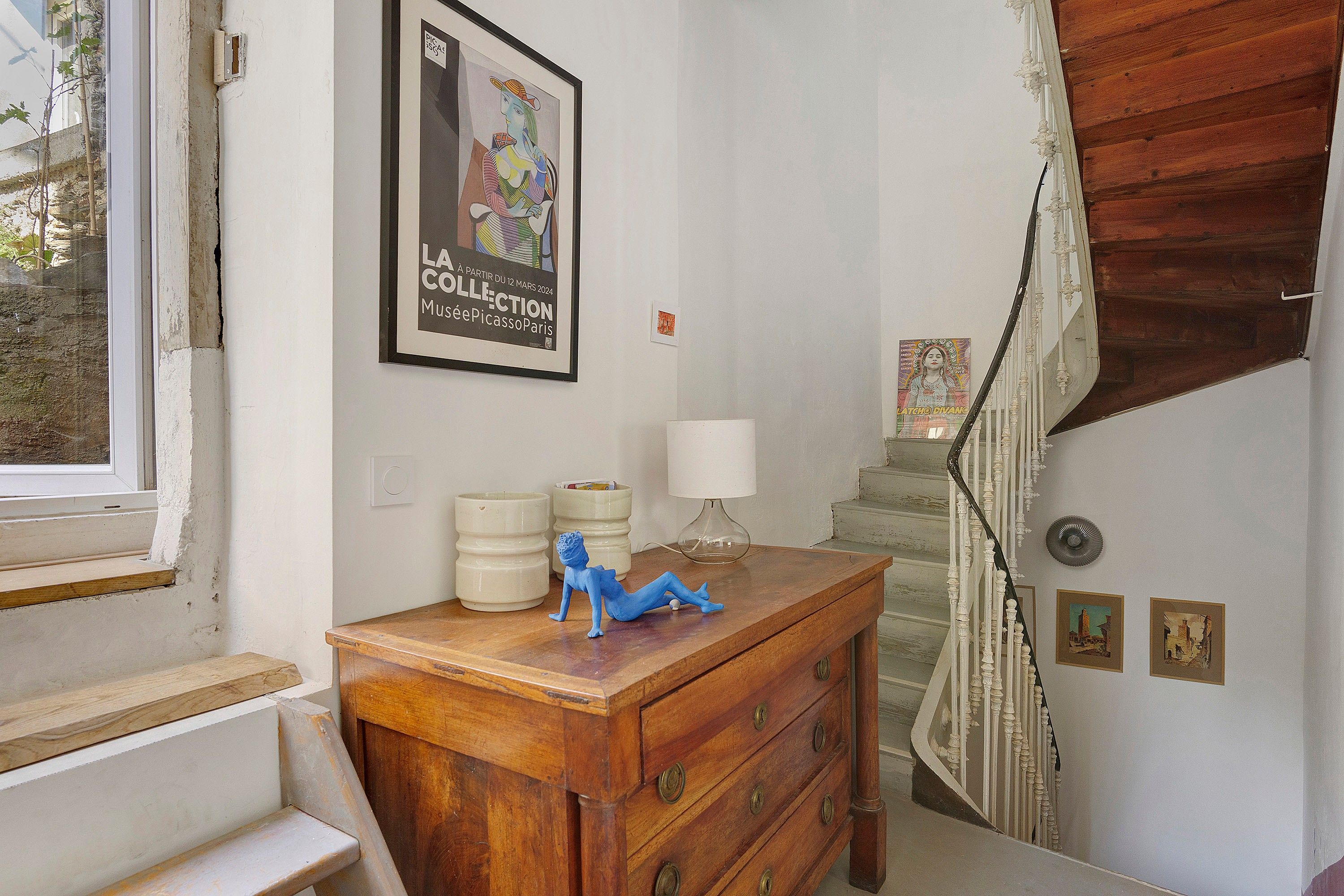 Una habitación con un tocador de madera, una lámpara y un cartel en la pared.