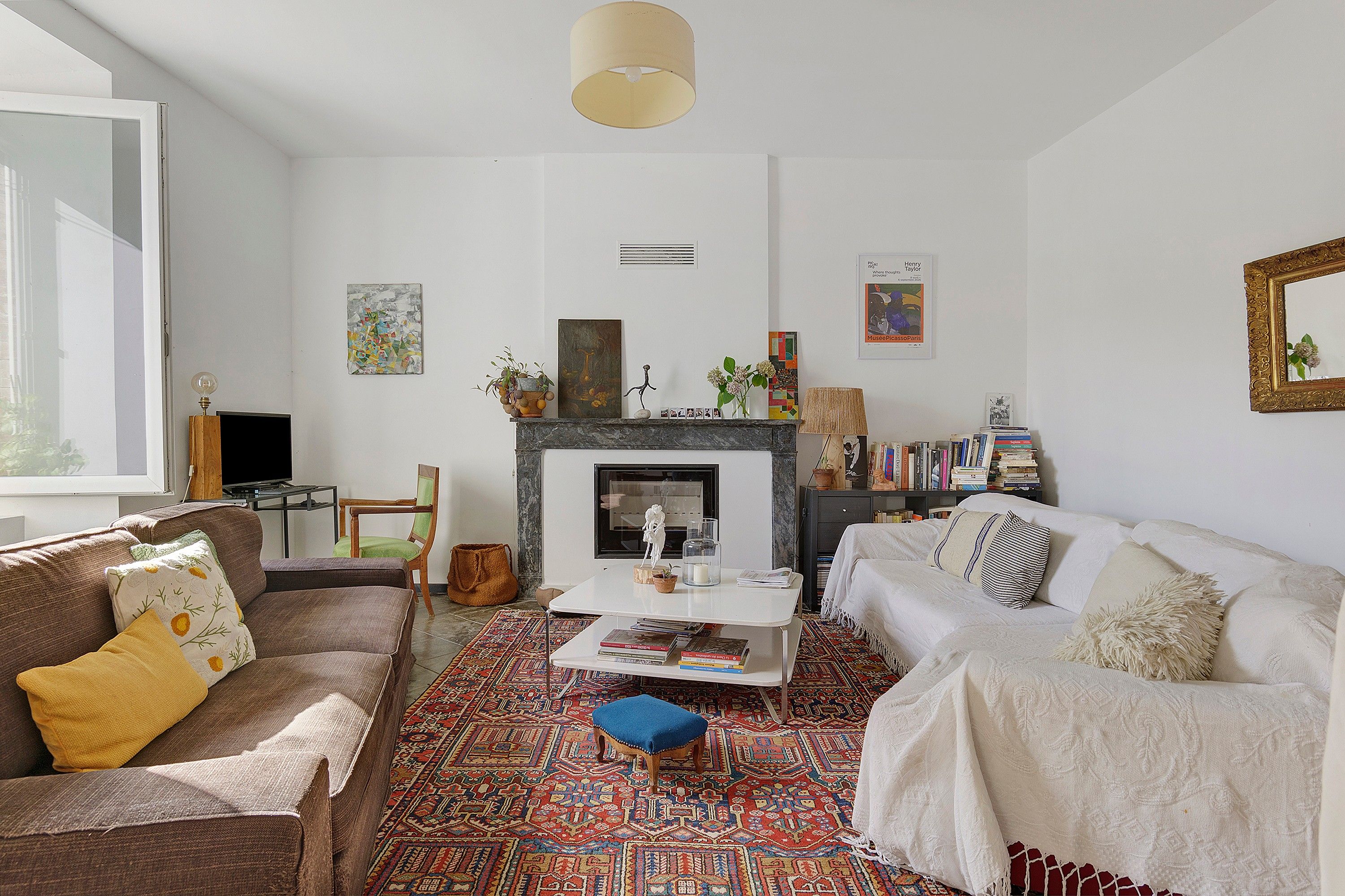 Een woonkamer met een open haard, een bank, een salontafel en een boekenkast.