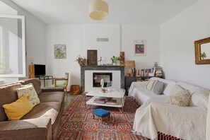 Ett vardagsrum med en öppen spis, en soffa, ett soffbord och en bokhylla.