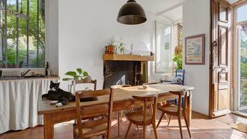 Een eetgedeelte met een houten tafel en stoelen, een hanglamp en een open haard.
