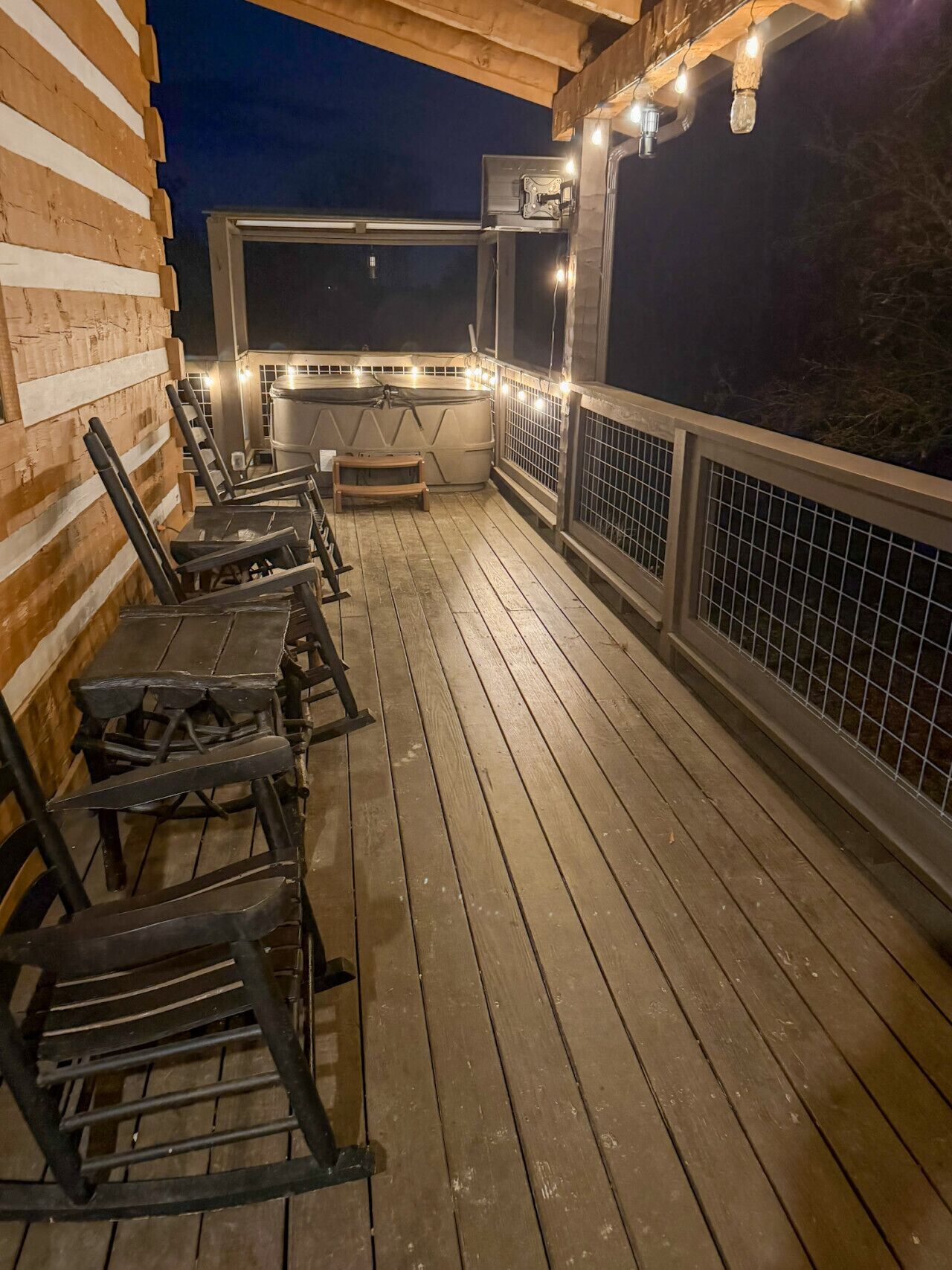 Une terrasse extérieure dotée d’un plancher en bois, de rampes en métal et d’une série de tables et de chaises.