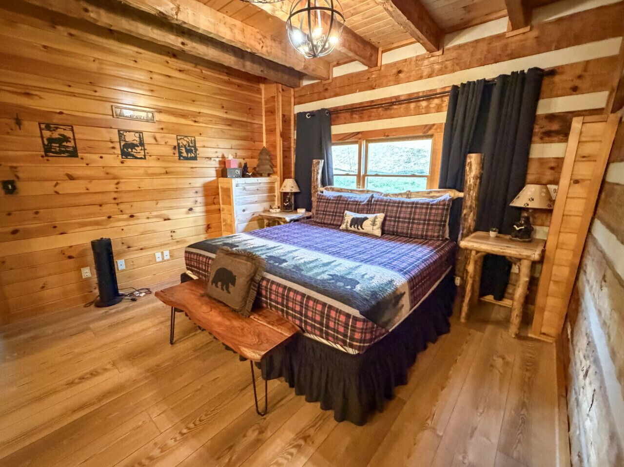 Ein gemütliches Schlafzimmer in einer Blockhütte mit Bett, Bank, Nachttisch und einem Fenster mit Vorhängen.