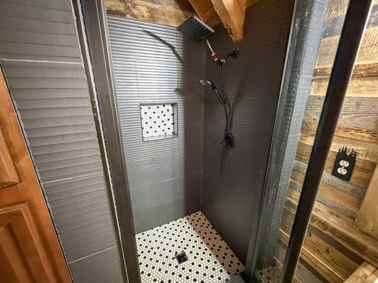 A small, enclosed shower area with a tiled floor and a showerhead mounted on the wall.