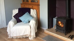 A cozy living room with a wooden cabinet, a fireplace, and a comfortable chair. - Jerry's Cottage, Dingle Penninsula Wild Atlantic Way and Páirc Nasiúnta na Mara  (Co)