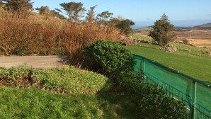 A grassy field with a green fence, trees, and a clear sky. - Jerry's Cottage, Dingle Penninsula Wild Atlantic Way and Páirc Nasiúnta na Mara  (Co)