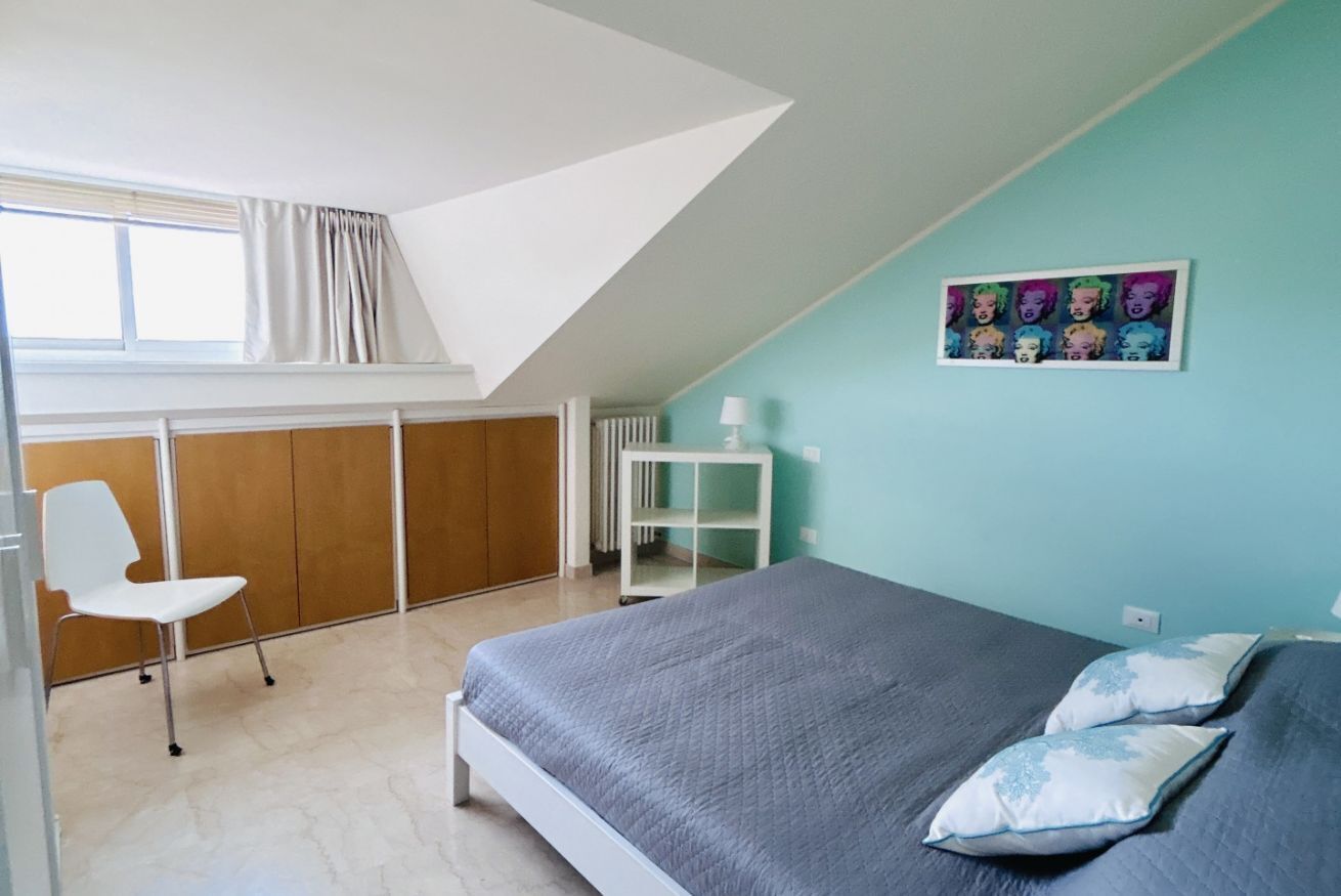 Quarto com cama, uma cadeira, um radiador e uma janela.