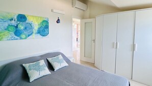 A bedroom with a bed, a wardrobe, and a painting on the wall. - Attic Gardens Flexrent - Abyssinia (Riccione)