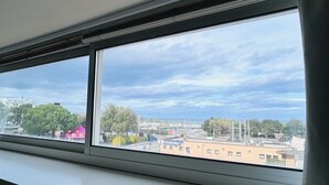 A view through a window with a parking sign and buildings in the distance. - Attic Gardens Flexrent - Abyssinia (Riccione)