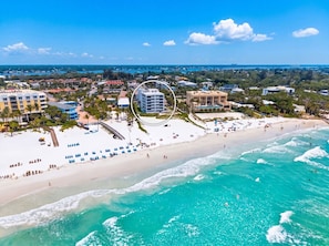An aerial view of a coastal area with a beach, a hotel with multiple floors, and a clear blue sky. - Relax and unwind at Villa 212 in Siesta Sands (Sarasota)