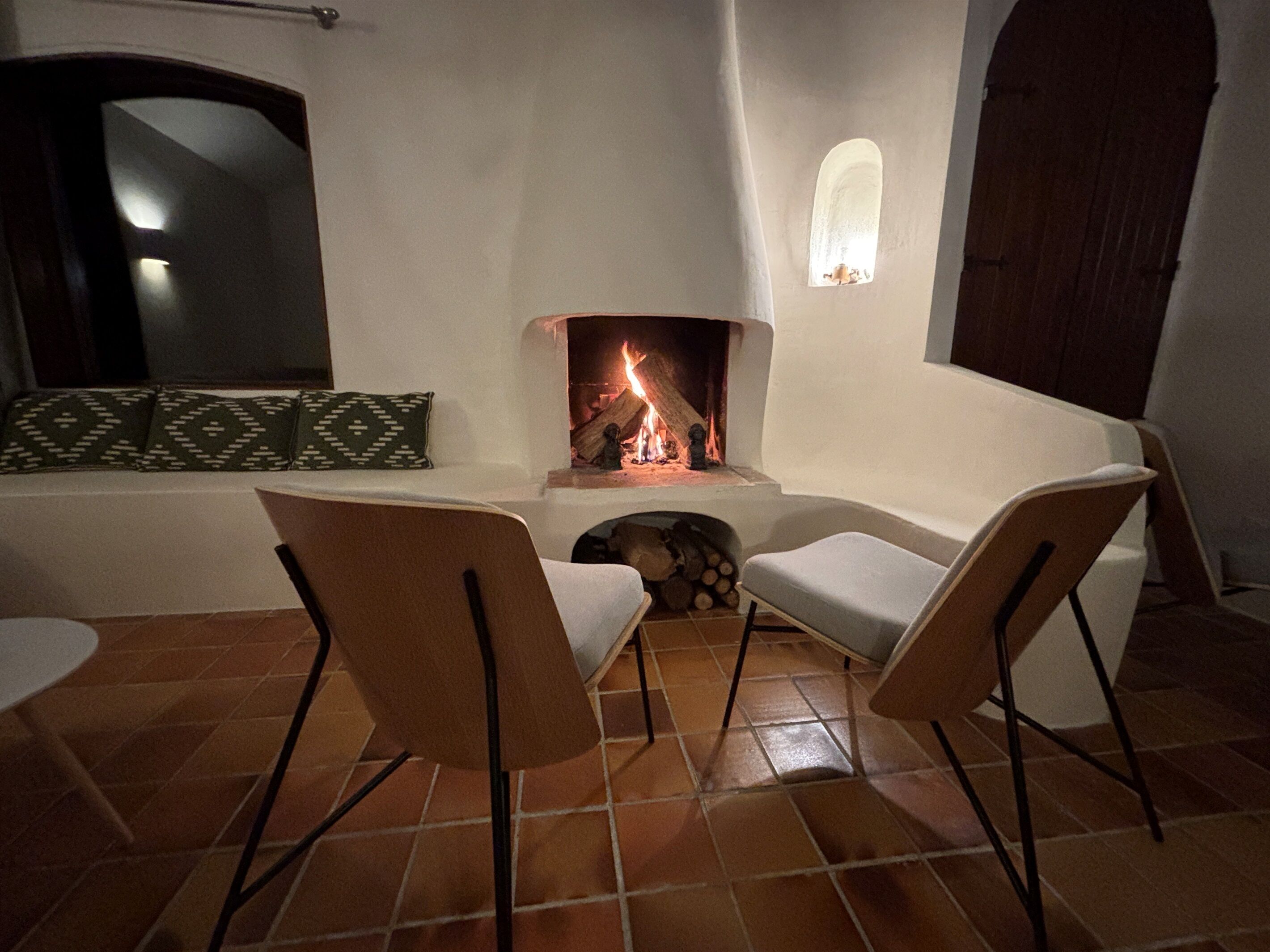 A cozy room with a fireplace, two chairs, a sofa, and a tiled floor.