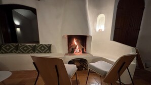 Ein gemütliches Zimmer mit Kamin, zwei Sesseln, einem Sofa und einem Fliesenboden.