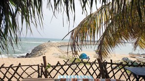 A beach view with a wooden fence, a striped towel, and a boat named "Lester Lion" in the background.