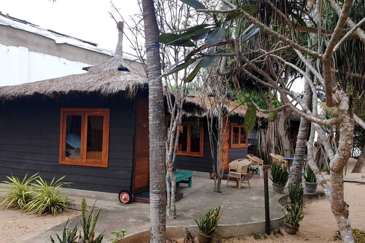 A thatched-roof house with a small porch and potted plants.