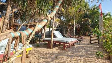 Zona de playa con sillas de descanso y una estructura de techo de paja.