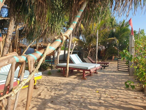 A beachside area with lounge chairs and a thatched structure.