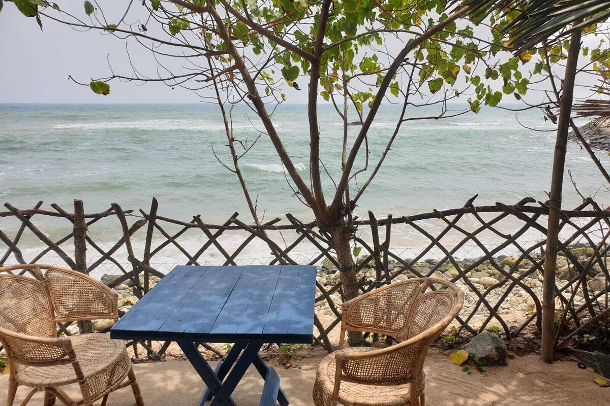 A beachside table with two wicker chairs, overlooking the ocean.