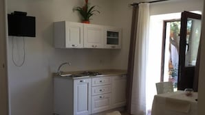 A bedroom with a bed, a small kitchenette, a bathroom with a shower, and a dining area with a table and chairs. - IL GIARDINO DI DANIELA APARTMENTS (San Teodoro)