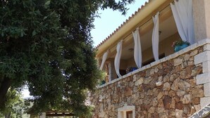 A stone building with a covered outdoor area, a stone staircase, and a table with a potted plant. - IL GIARDINO DI DANIELA APARTMENTS (San Teodoro)
