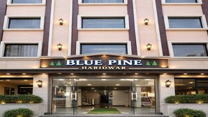 Blue Pine Haridwar -niminen hotelli, jossa on moderni julkisivu, useita ikkunoita ja hyvin valaistu sisäänkäynti.