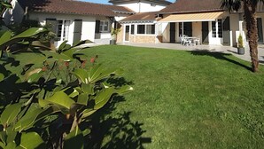 A residential property with a well-maintained lawn, outdoor seating area, and a patio with chairs and tables. - “Agapanthe” Guest Room – Suite with Breakfast Included (Feytiat)
