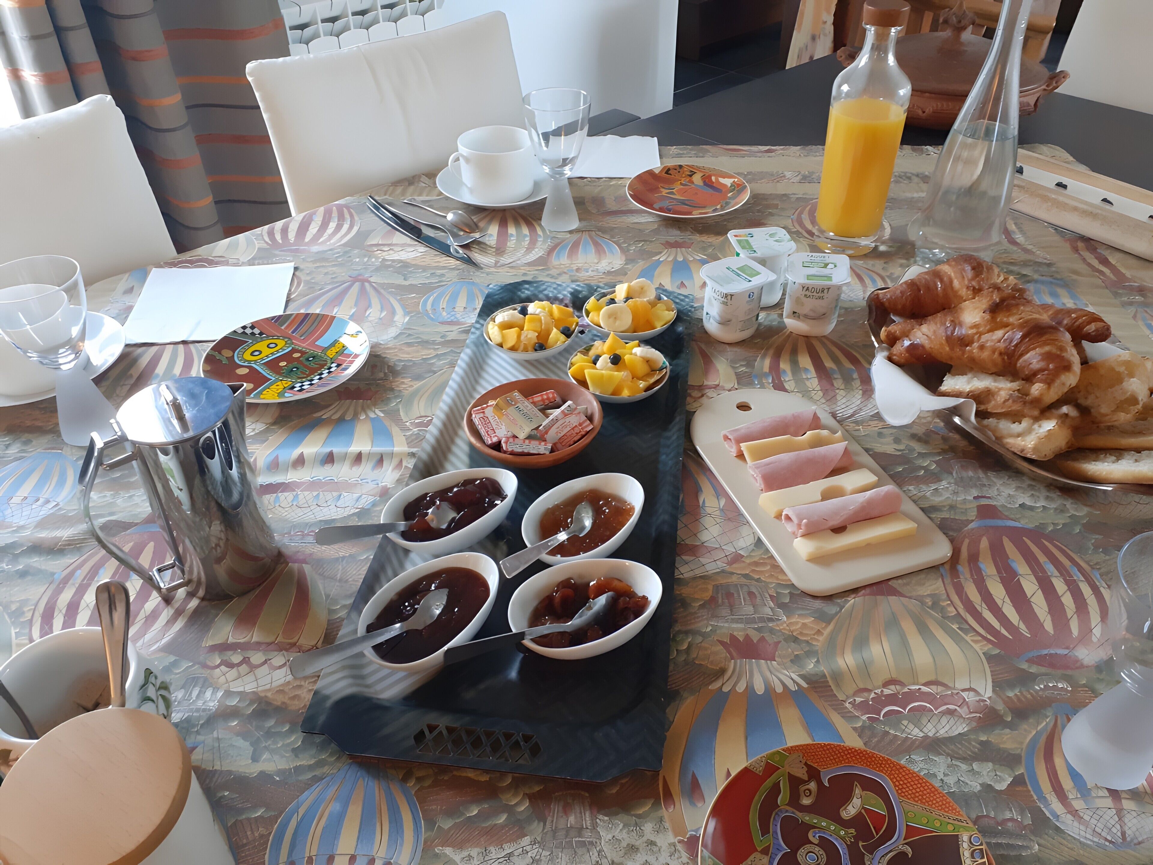 Ein Esstisch mit verschiedenen Speisen, Gewürzen und einem Krug Orangensaft.