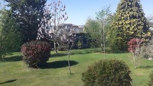 A well-maintained garden with various trees and shrubs, a clear sky, and a building in the background. - “Agapanthe” Guest Room – Suite with Breakfast Included (Feytiat)