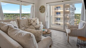 A spacious balcony with a ceiling fan, a sofa set, and a chair. - 1BR Luau Condo on 7th Floor with spanning views of the lagoon pool and Gulf at Sandestin Golf & Beach Resort (Miramar Beach)