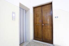 A wooden double door with a handle, a light switch, and a small window on the wall. - GuesHost - Positano Apartment in Salerno (Salerno)