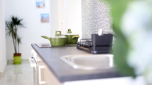 A kitchen with a modern design, featuring a stainless steel countertop, a sink, and green cookware. - GuesHost - Positano Apartment in Salerno (Salerno)