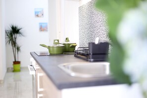 A kitchen with a modern design, featuring a stainless steel countertop, a sink, and green cookware. - GuesHost - Positano Apartment in Salerno (Salerno)