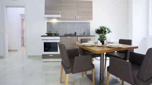A modern kitchen with a dining area, featuring a wooden cabinet, a tiled backsplash, and a dining table with chairs. - GuesHost - Positano Apartment in Salerno (Salerno)