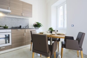 A modern kitchen with wooden cabinets, a dining table with chairs, and a window providing natural light. - GuesHost - Positano Apartment in Salerno (Salerno)