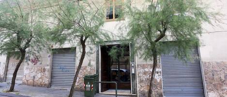 A building with a stone facade, a metal door, and a green trash bin.