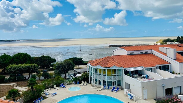 A hotel with a swimming pool, lounge chairs, and a view of the beach. - Apartment with sea view - 4 guests (Fouras)