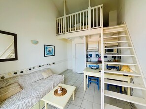 A compact living space with a bunk bed, kitchenette, dining area, and a sofa. - Apartment with sea view - 4 guests (Fouras)