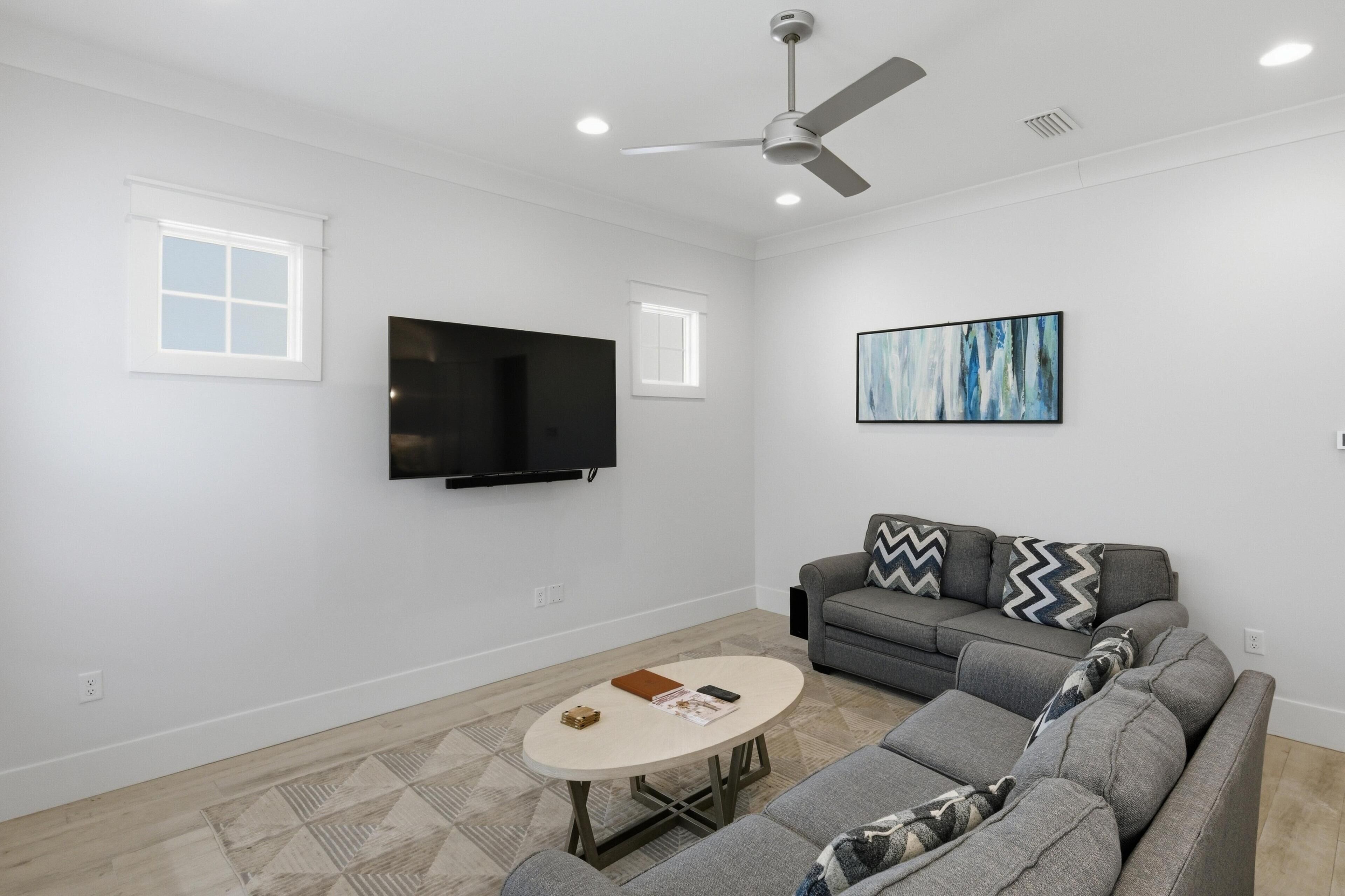 Ein Wohnzimmer mit Sofa, Couchtisch, Fernseher und Deckenventilator.