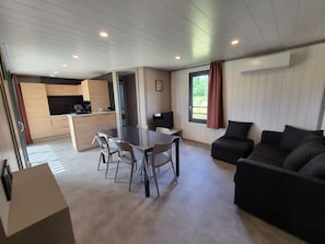 Un espace de vie moderne comprenant une table à manger, un canapé, un coin cuisine et de grandes fenêtres.