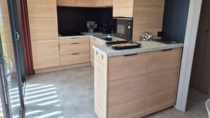 A modern kitchen with wooden cabinets, a built-in oven, and a countertop with a baking tray. - Comfort Chalet with AC & Parking / 2 Bedrooms (Marzan)