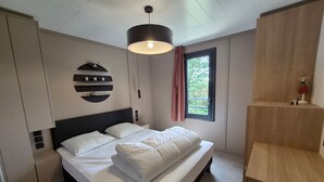 A bedroom with a bed, a wall-mounted shelf, a window with a view, and a pendant light. - Comfort Chalet with AC & Parking / 2 Bedrooms (Marzan)