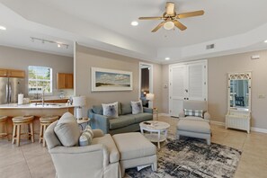 Ein modernes Wohnzimmer mit einer Couch, Sesseln, einem Couchtisch und einem Deckenventilator.